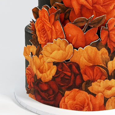 Dark Floral Cutout Wedding Cake with bright sugar flowers on a white board