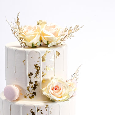 Gold Leaf Wedding Cake with white drip, blush roses, dried grasses, gold leaf and a pink macaron