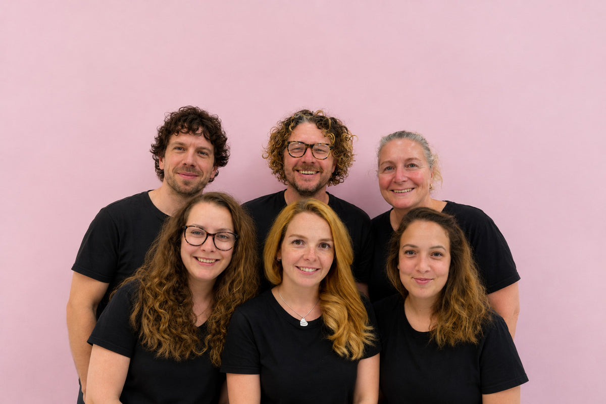The Harry Batten bakery team in black T-shirts against a pink wall