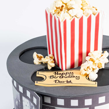 Movie Cake shaped like a film reel with a popcorn box and a fondant cinema ticket birthday message