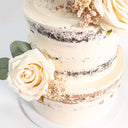 Two tier Naked Wedding Cake with white buttercream, cream roses and greenery