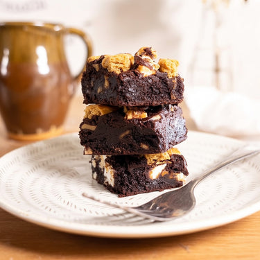 Stack of S'mores Brownies with marshmallows and biscuit pieces on a plate