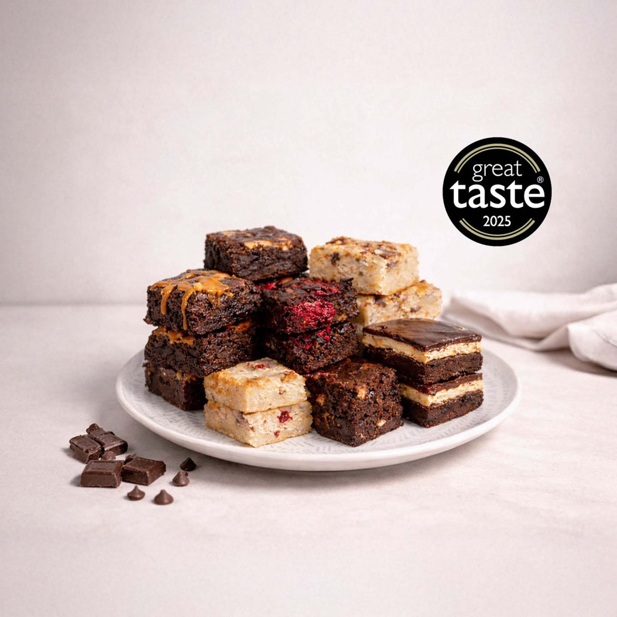 Wholesale Brownies: A plate of assorted brownies and blondies, featuring various flavors, alongside chocolate squares and chips. Includes award badge for taste excellence.