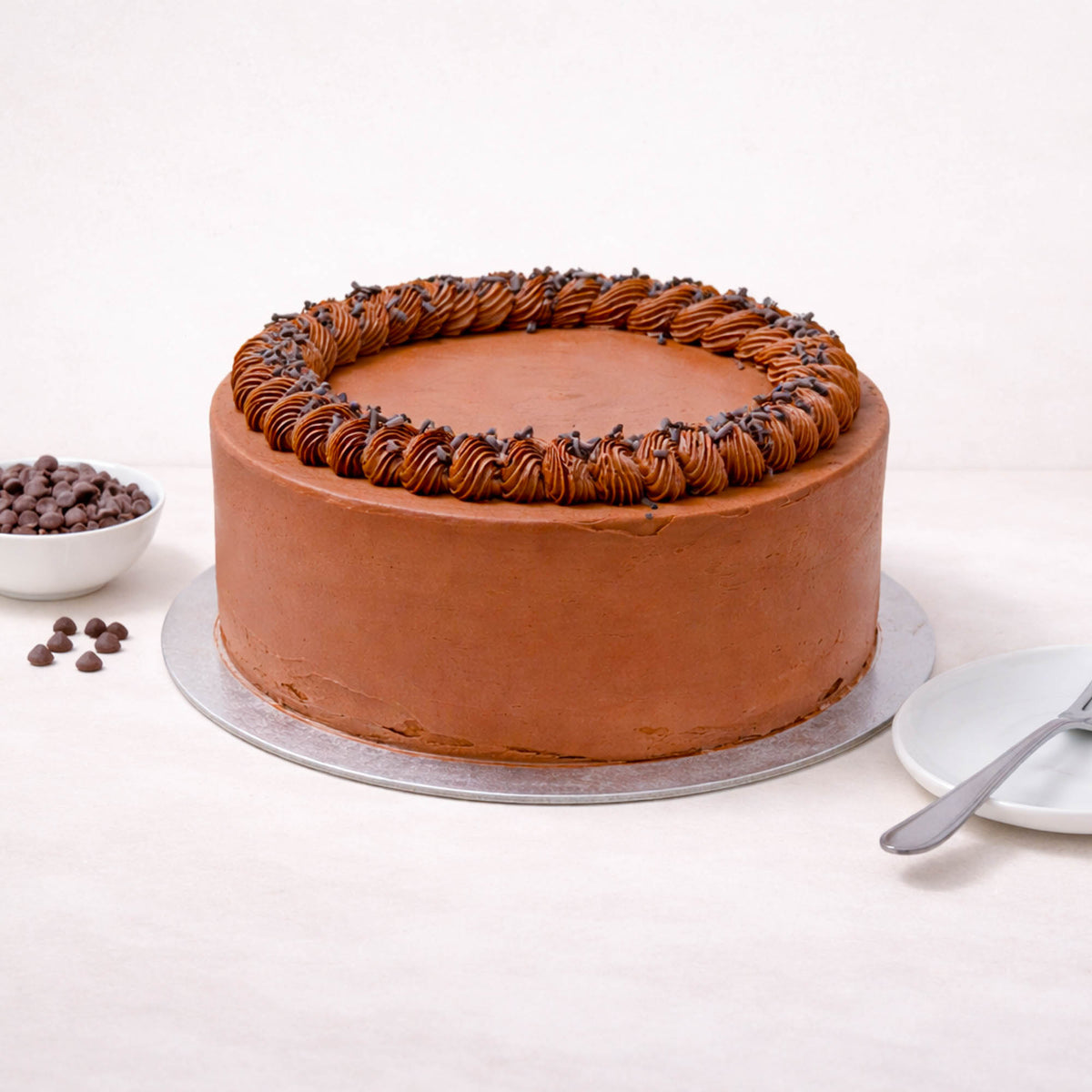 Chocolate Cake with piped buttercream and chocolate chips on a silver board
