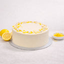 Lemon Drizzle Cake with lemon curd and meringue crumbs, next to lemons and zest