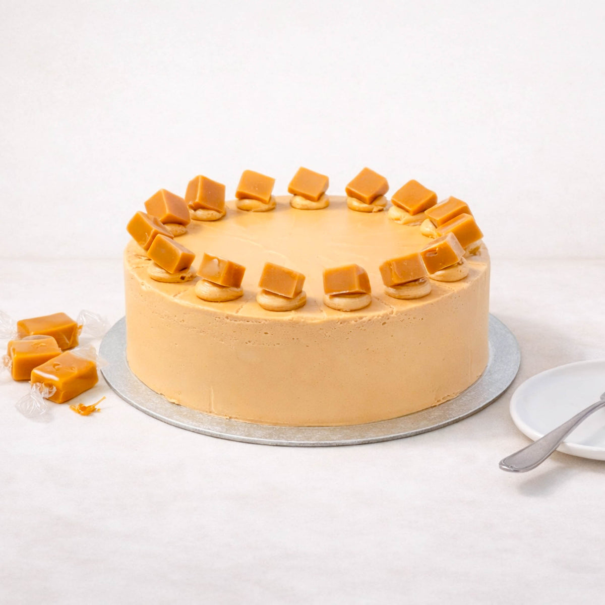 Salted Caramel Cake with smooth buttercream and caramel pieces on a silver board