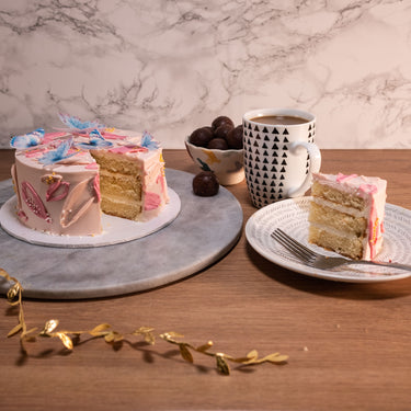 Mini Butterfly Cake with blue butterflies, with a slice on a plate and a mug of coffee