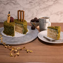 Mini Cricket Cake with green crumb grass and cricket decorations, with a slice on a plate and a mug