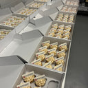 Boxes of branded cupcakes with buttercream, gold sprinkles and edible logo plaques, ready for delivery