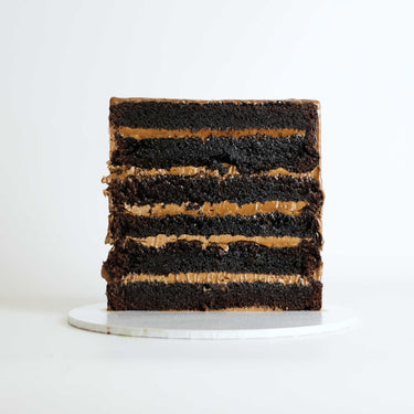 Free From Triple Chocolate Cake with chocolate drip and handmade chocolates on a white cake board